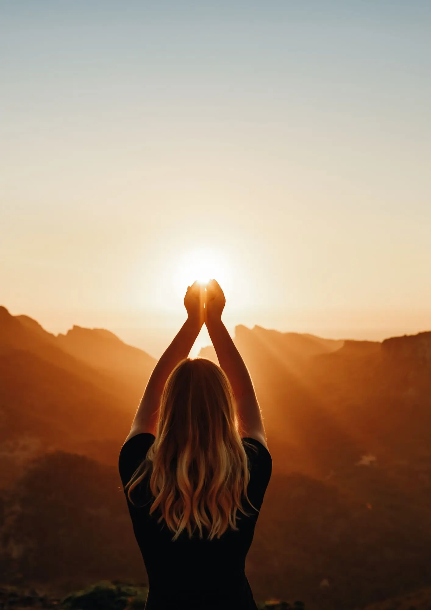 Lady holding hands up towards sun