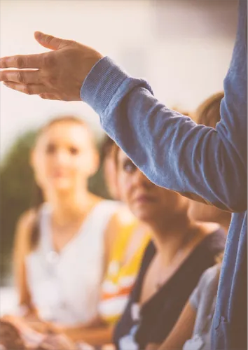Teacher standing in front of class in blue cardigan